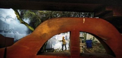 Un bombero limpia con una manguera el garaje de la casa de Noel Piri que fue destruida por el incendio de Hawarden en Riverside, California, el domingo 21 de julio de 2024. (Terry Pierson/The Orange County Register vía AP)